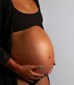 Woman with hands on pregnant belly.